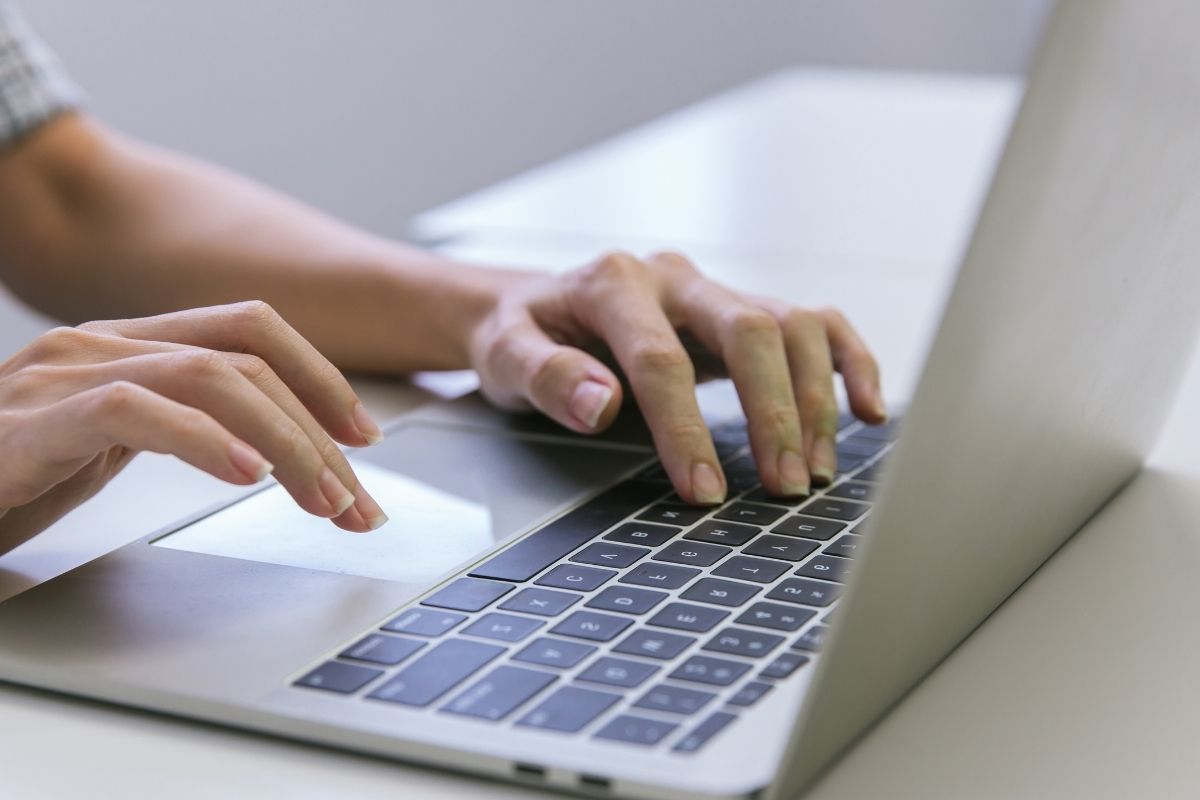 The photo of a woman's hand using a laptop for a website tester.