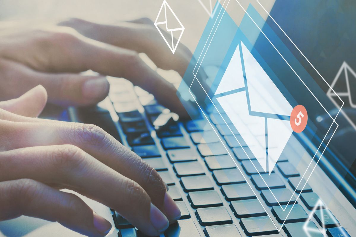 The photo shows a man's hand working on his laptop as an email support agent.