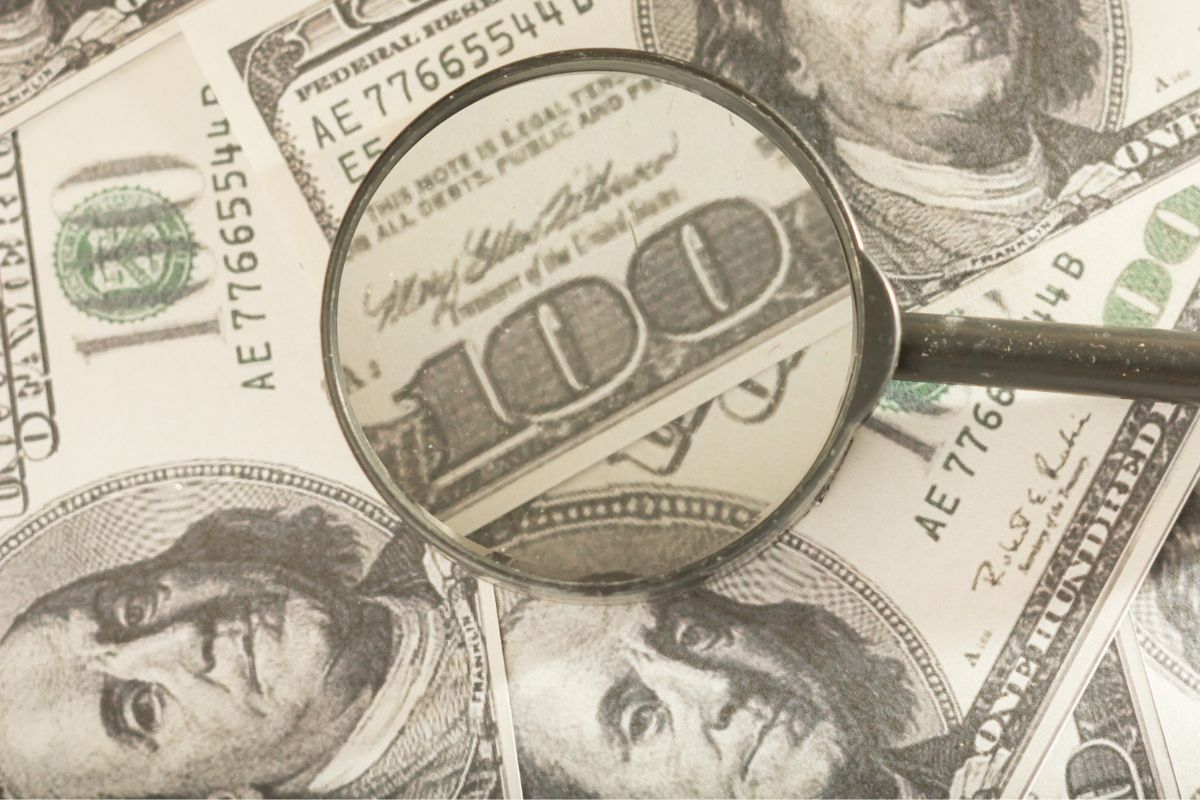 The image shows dollar bills and a magnifying glass indicating that money is scarce vs sees money as a tool. 