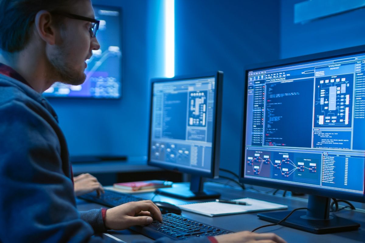 The picture shows a man working on his computer as a software developer.
