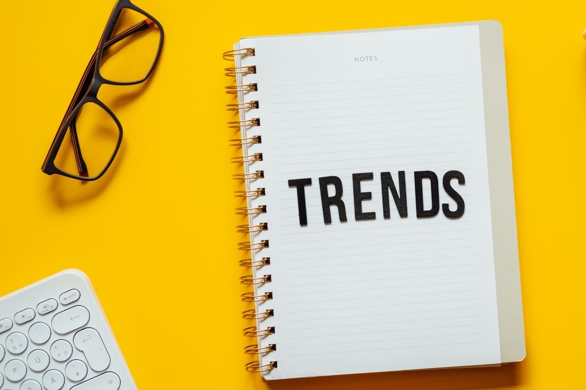 The picture shows a keyboard and a notebook with a note referring to keeping up with trends vs focusing on long-term goals