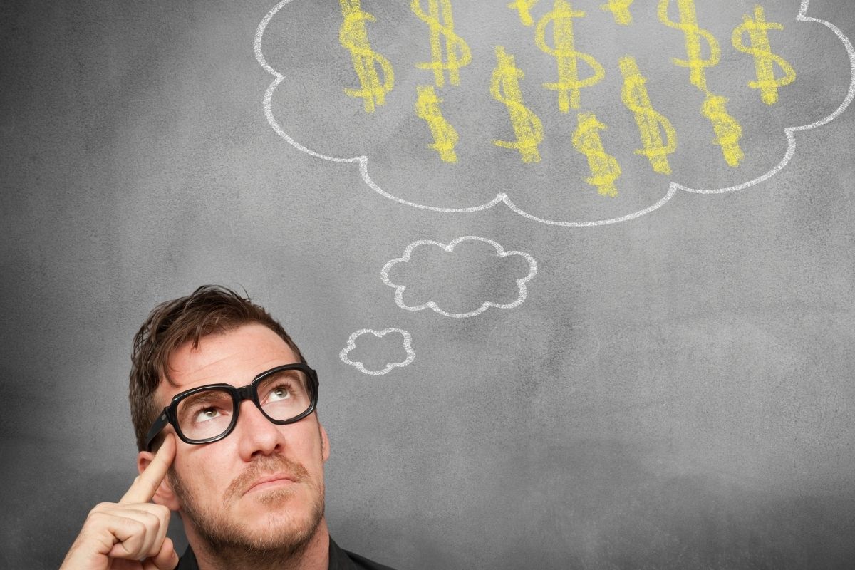 The photo shows a board with illustrations and a man thinking referring to thinks money is evil versus thinking money is freedom which refers to this mindset as a big piece of strong financial education.