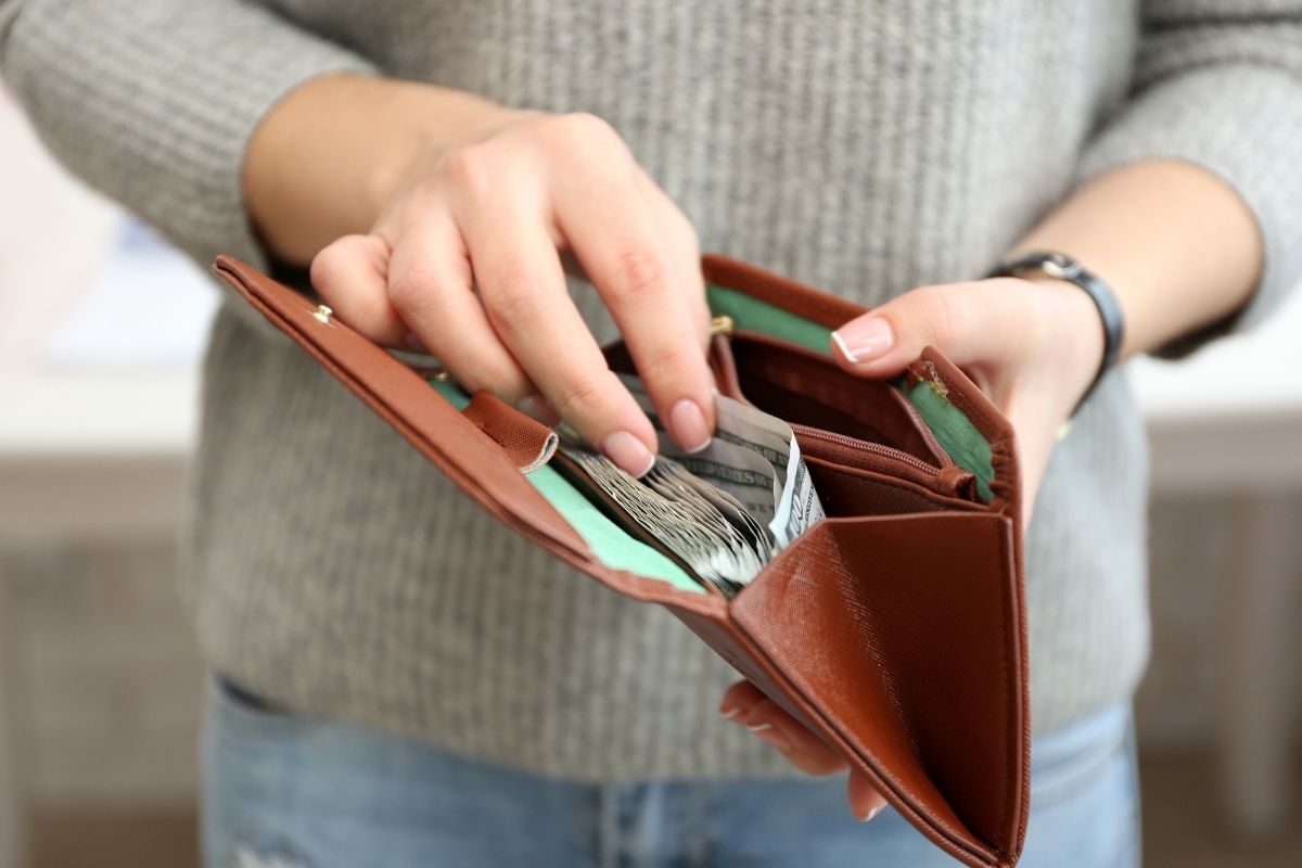 The image shows a women pulling out money from her wallet.