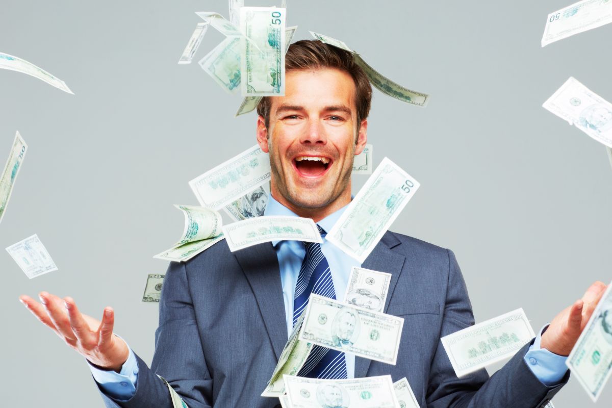 The photo of a man in a suit enjoying the fallen money refers to learning how to get rich,  finding easy tips and real-life money advice to help you get rich the smart way.