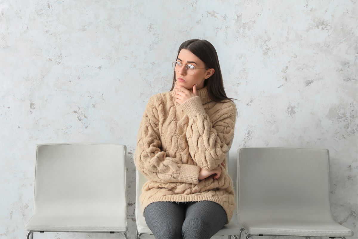 The image shows a women sitting on a chair while thinking 