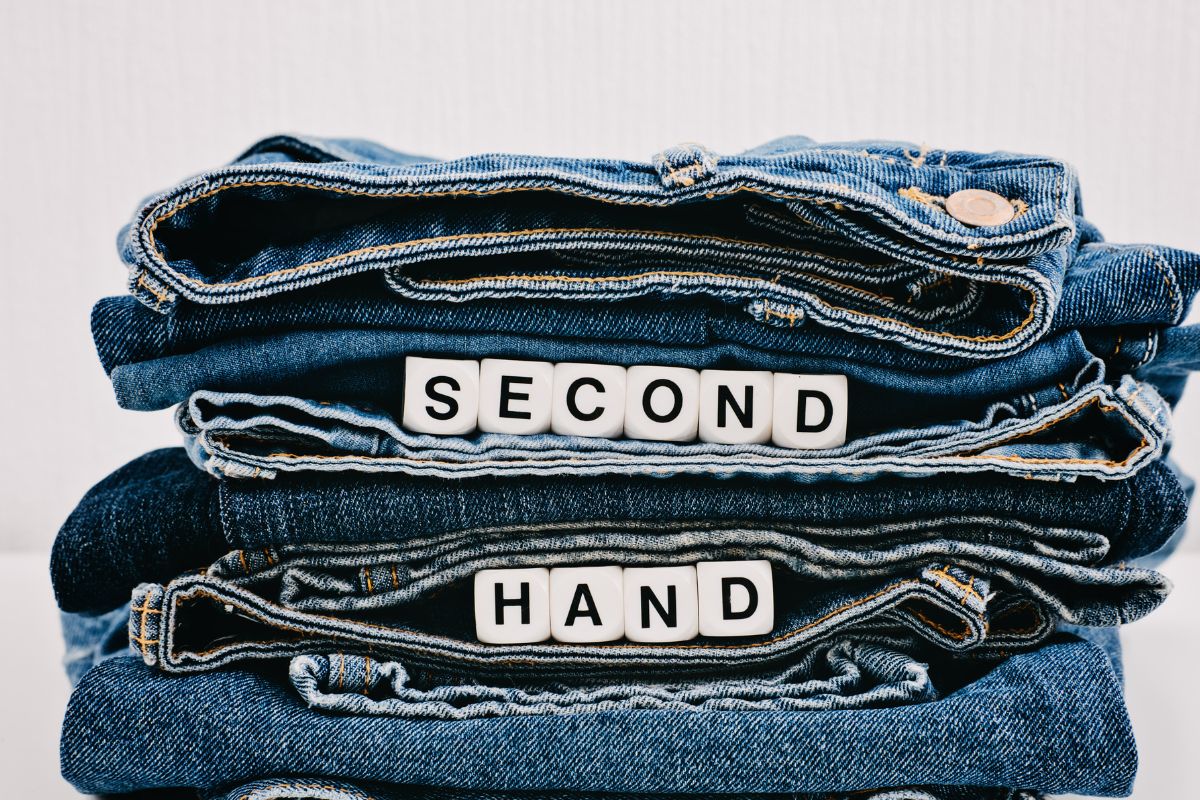The photo shows jeans with wooden cubes with letters referring to buying used.
