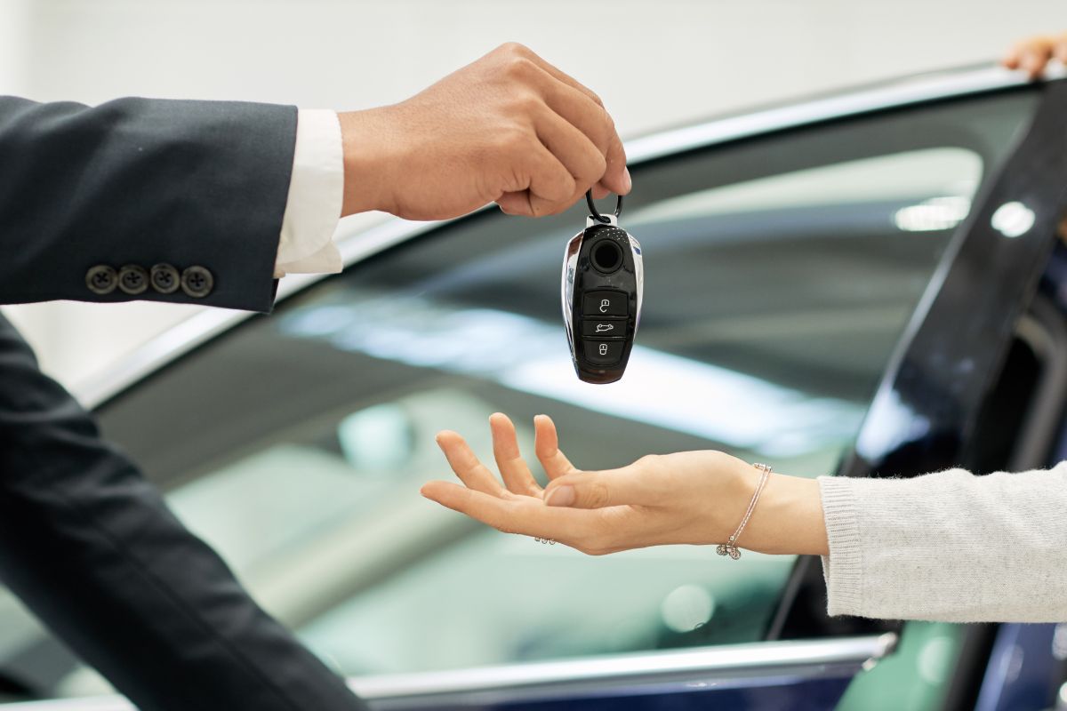 The photo shows the salesman handing over a set of keys to the buyer.