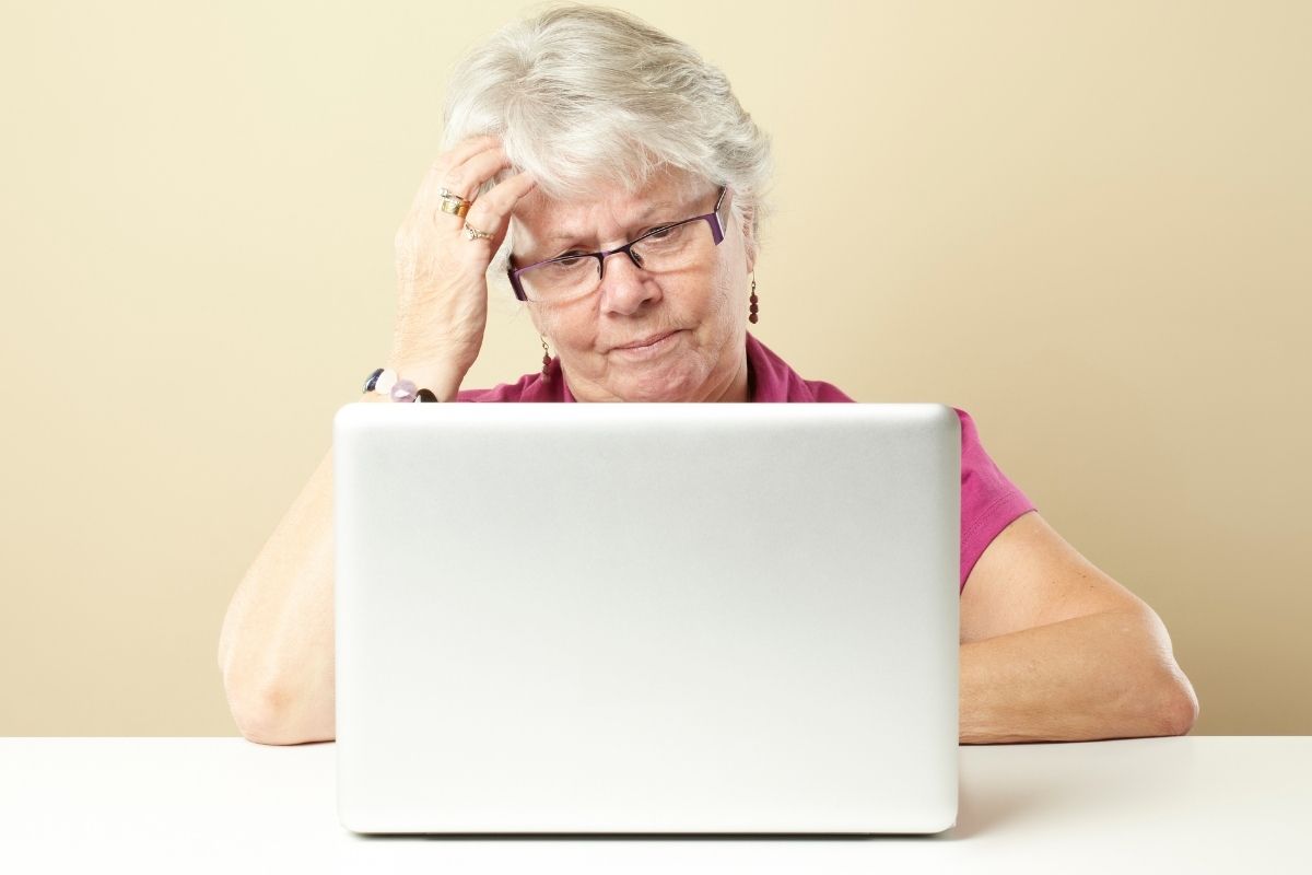The picture of a senior lady with financial worries while working on a laptop.