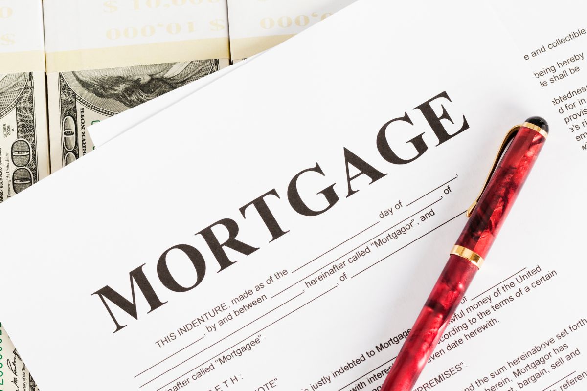 The photo shows dollar bills, papers with mortgage word, and a pen.