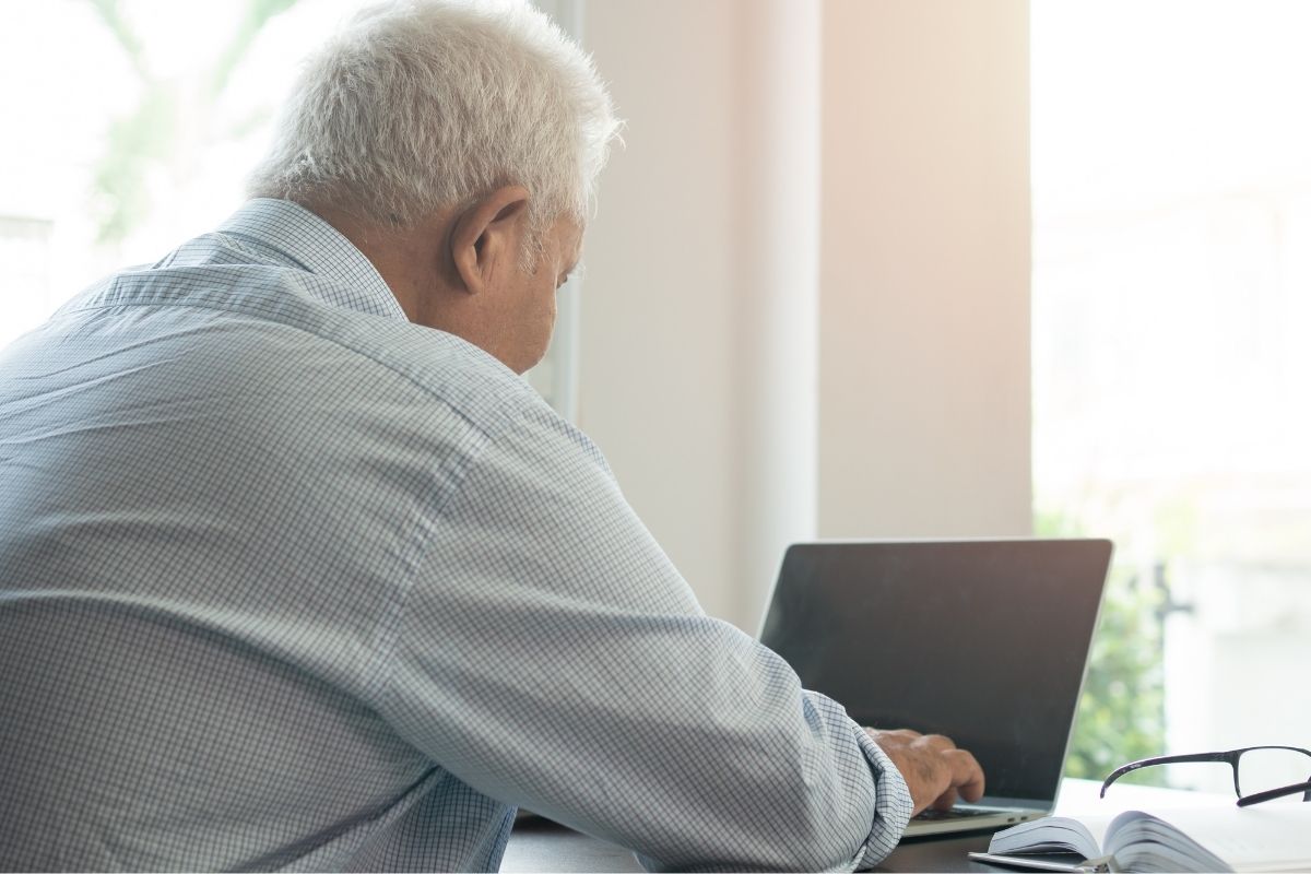The photo of a senior man working on his laptop.