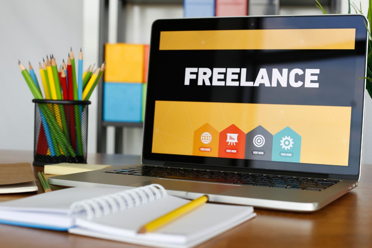 The image is about a pen, a notebook, and a laptop with freelance wording on the screen.