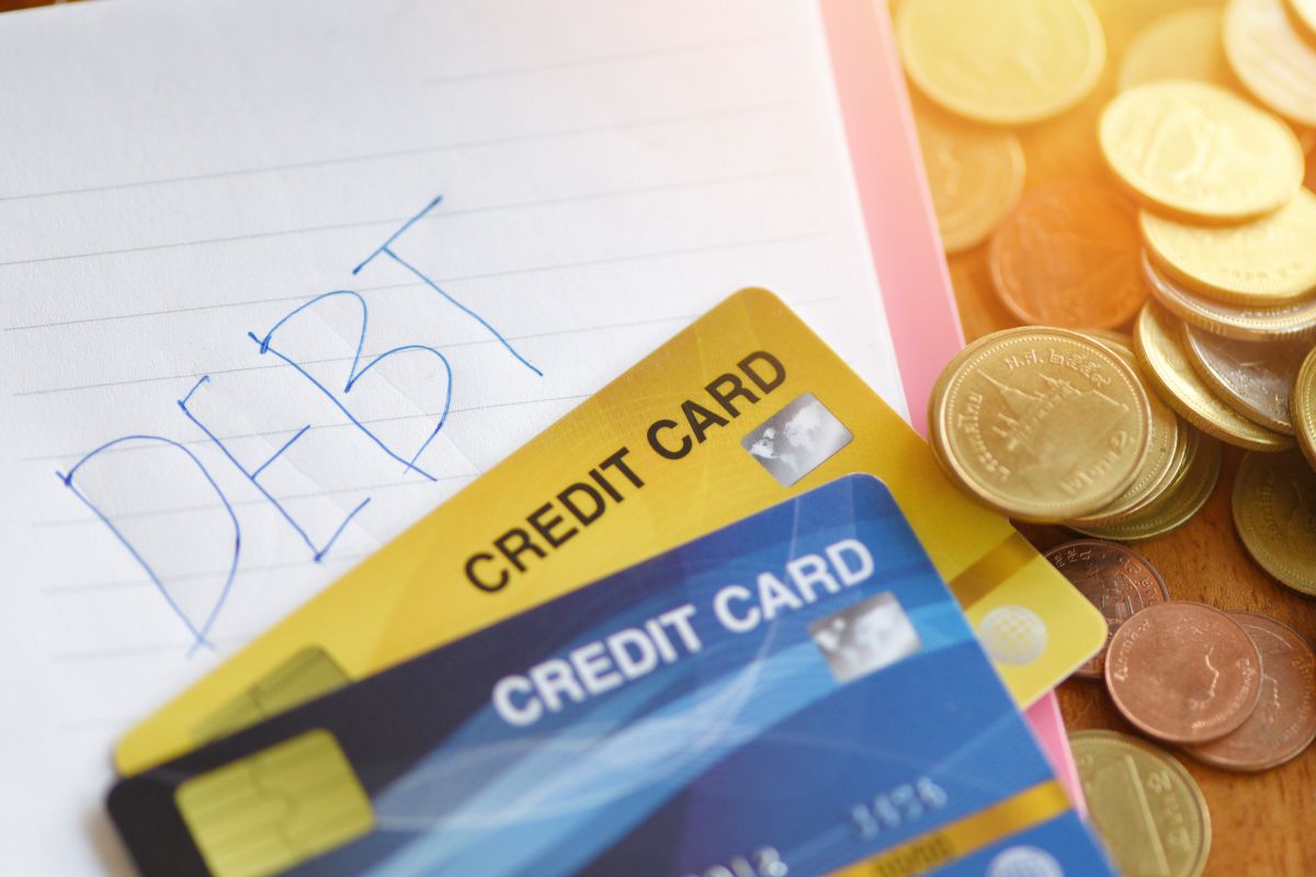 The image shows coins, credit cards, and a notebook.