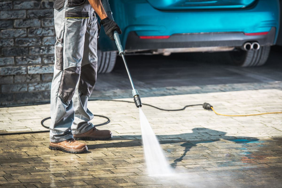 The picture shows a car and a man cleaning the floor.