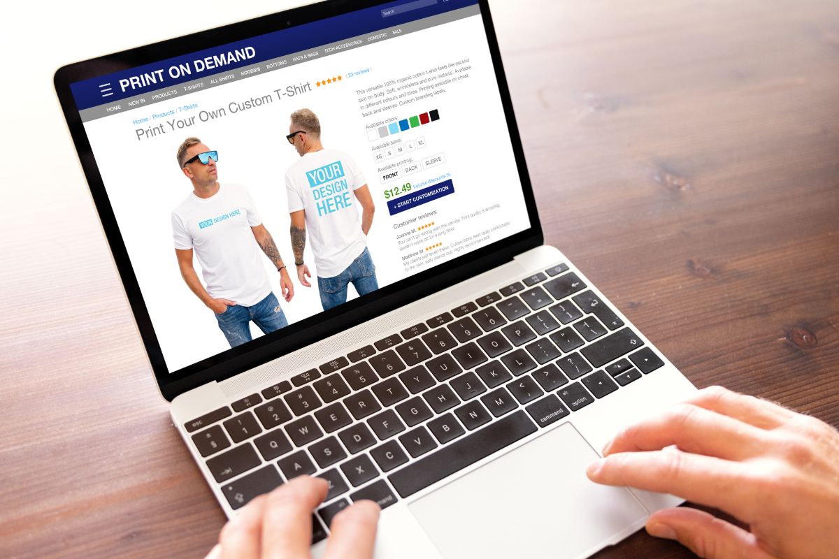 The photo shows a man's hand using a laptop.