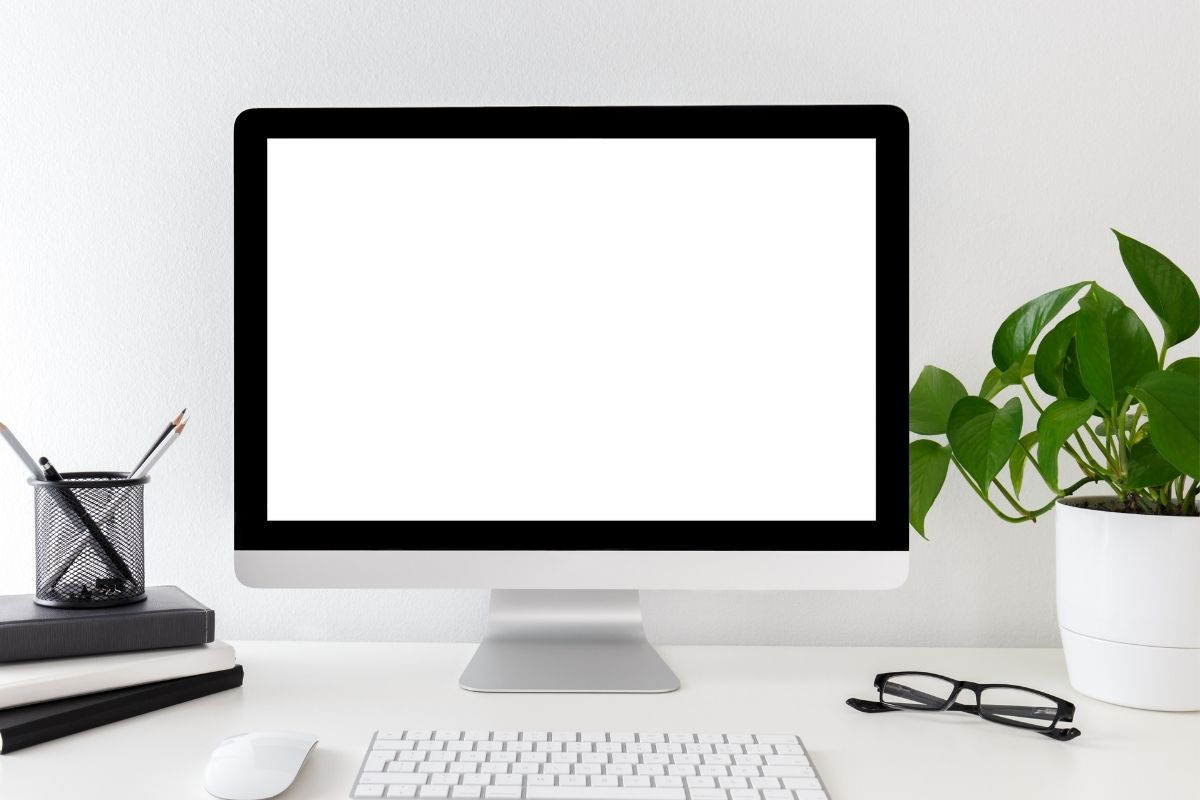 The image shows computer sets, plants, and a notebook on the table.