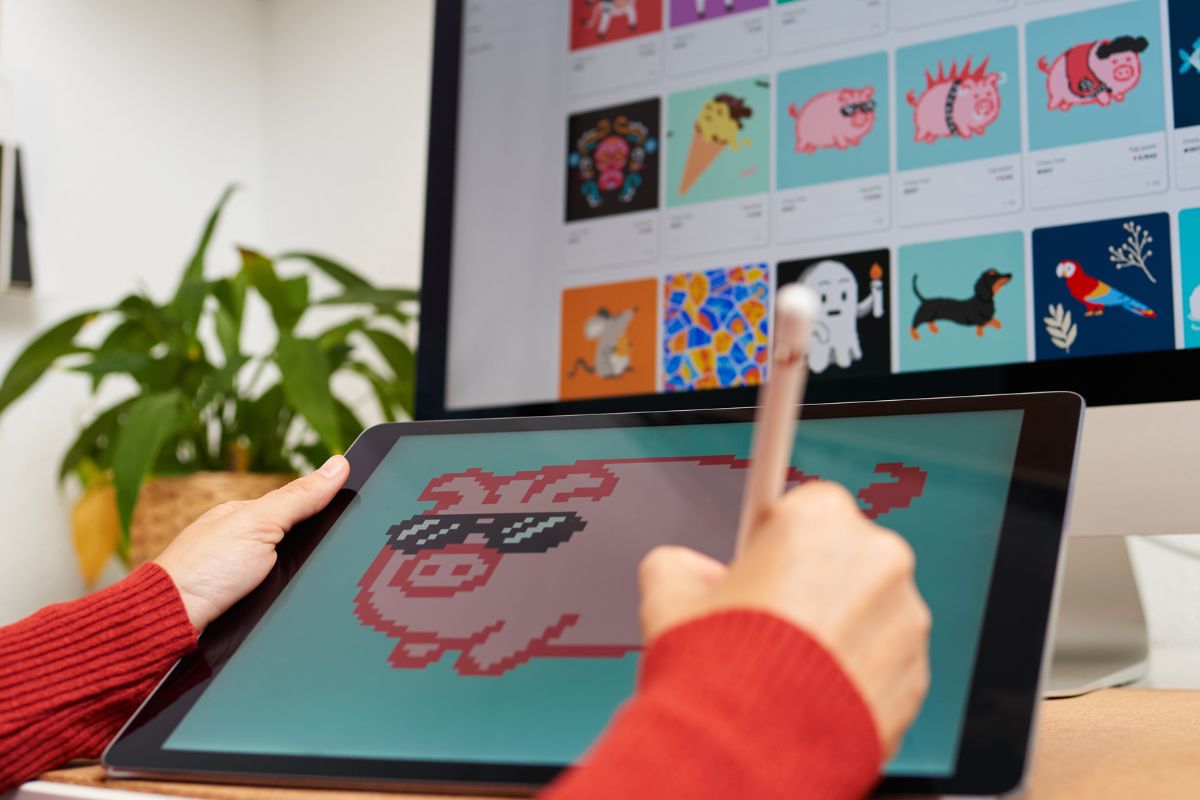 The photo shows a monitor and a lady's hand drawing on the tablet device.