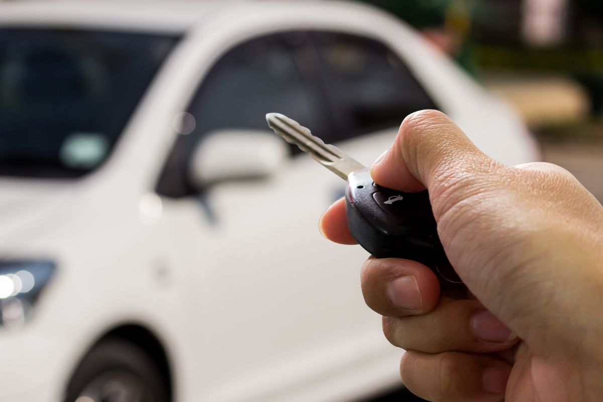 The image tells about a man's hand holding a key and a car.