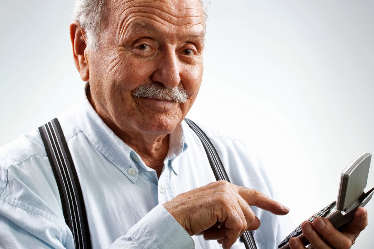 The image shows a senior man holding a calculator for a retirement budget.