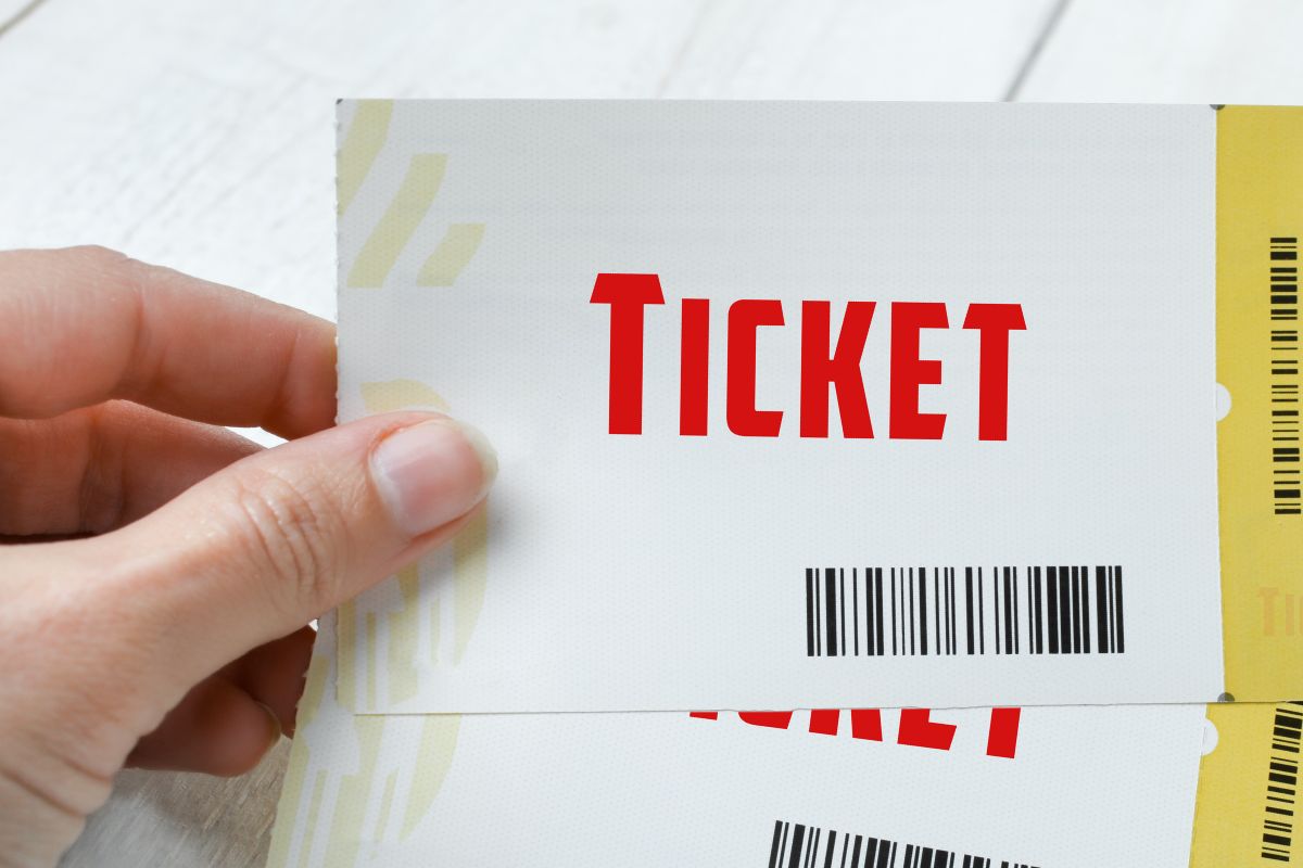 The photo of lady's hand holding event tickets.
