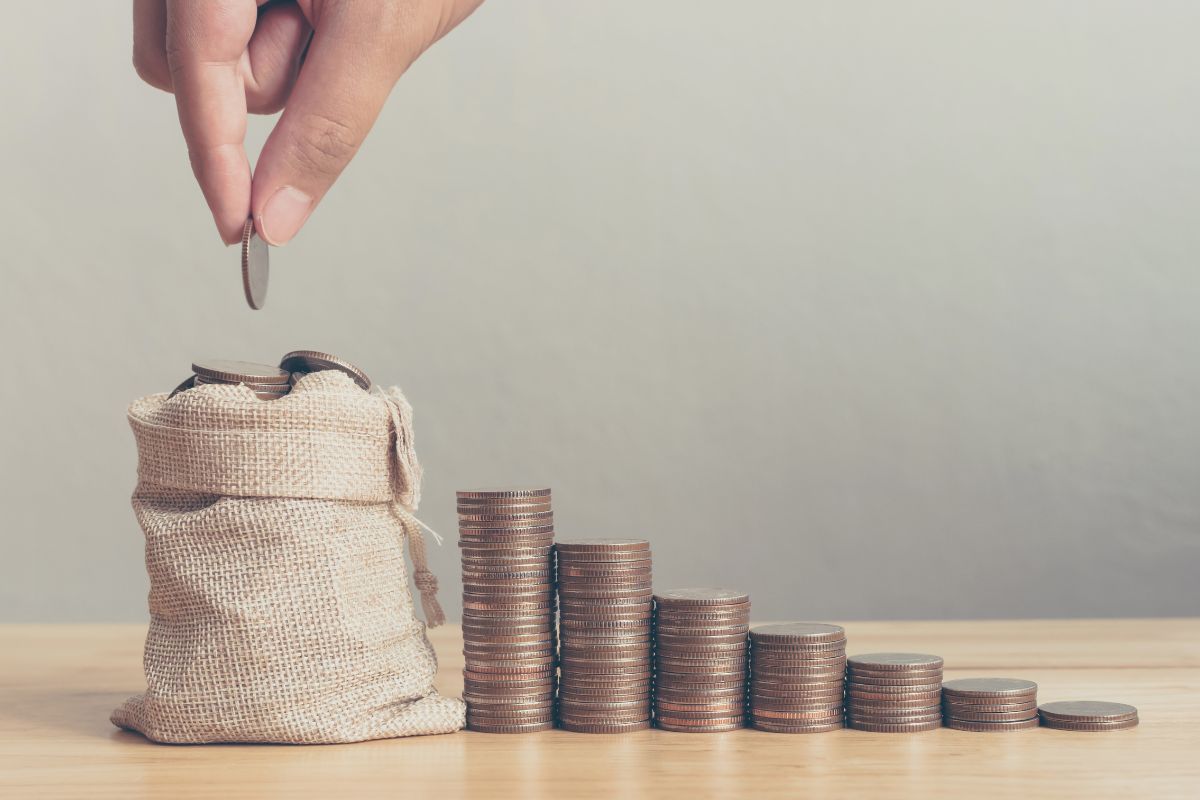 The image of stacked coins and a man's hand dropping a coin for savings early.