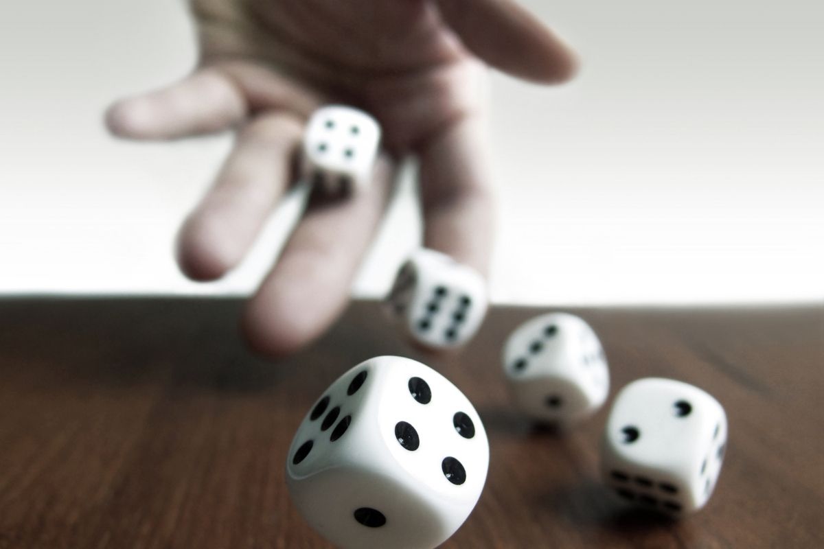 The photo shows a kid's hand rolling the dice on the floor.