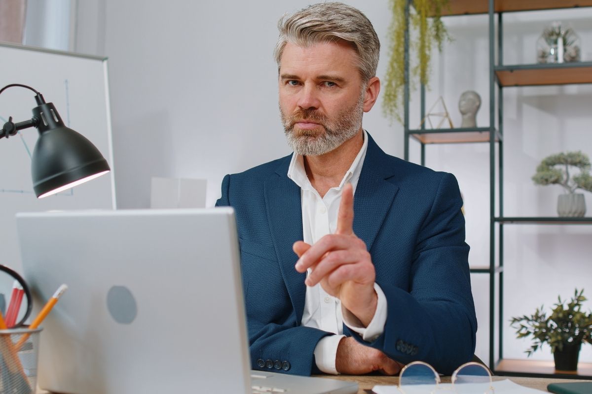 The picture of a busy senior man working on his laptop at his office.