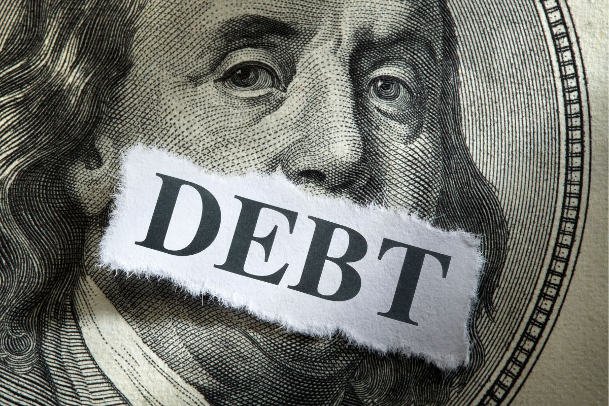 The picture tells about a dollar bill icon and a paper with debt word.
