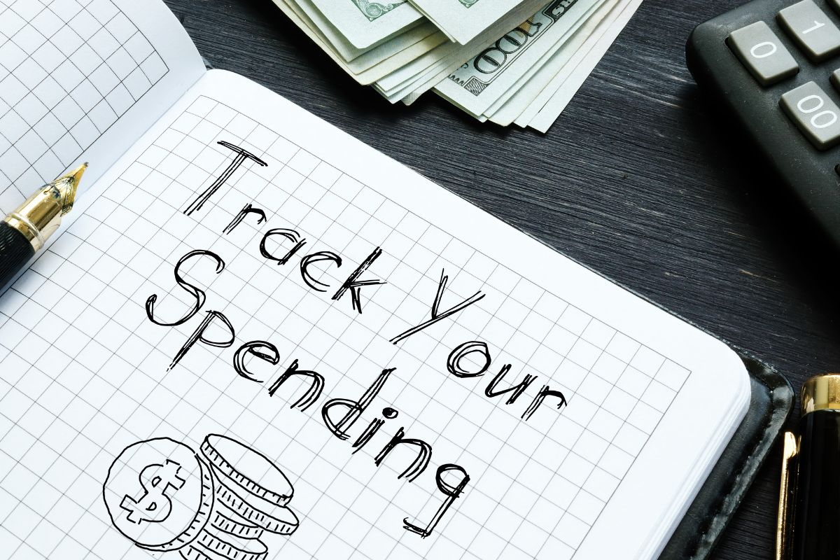 The picture of a notebook with notes, dollar bills, and a calculator on the table.