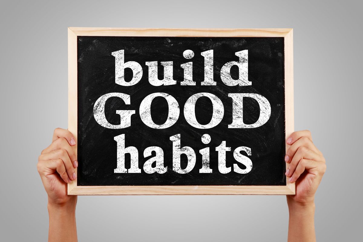 The image shows a lady's hand holding a board with Build good habits wordings.
