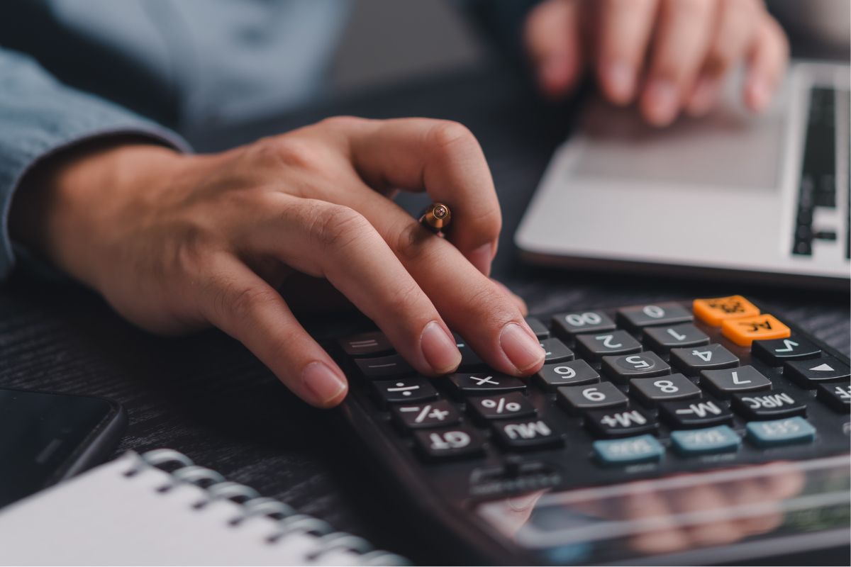 The picture shows a man's hand calculating to adjust the budget.