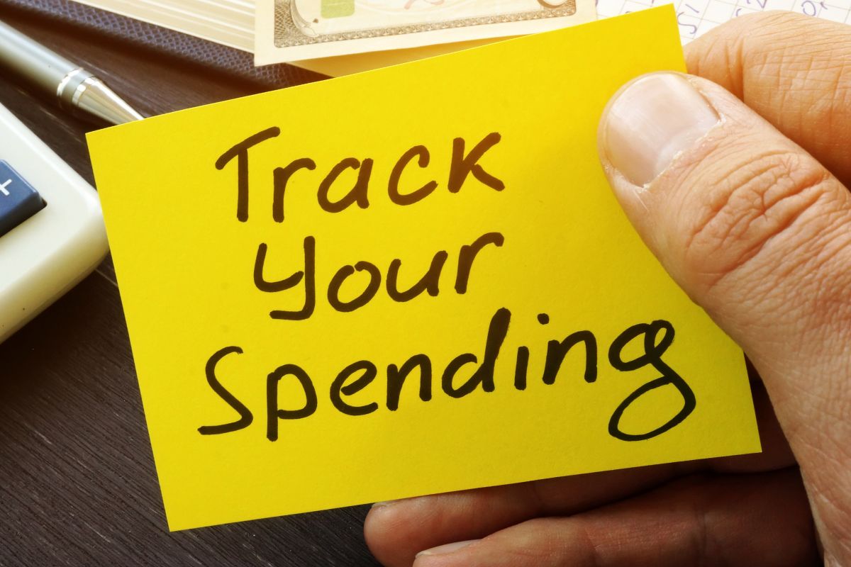 The image of a man's hand holding a piece of paper with the Track Your Spending wording.