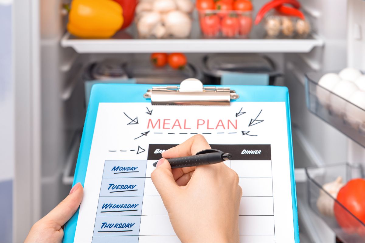 The picture is about a lady's hand making a meal plan.