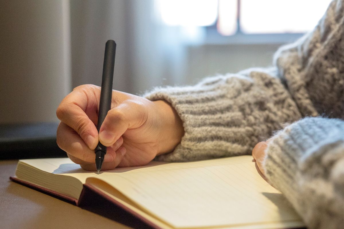 The image shows a lady's hand making a list.
