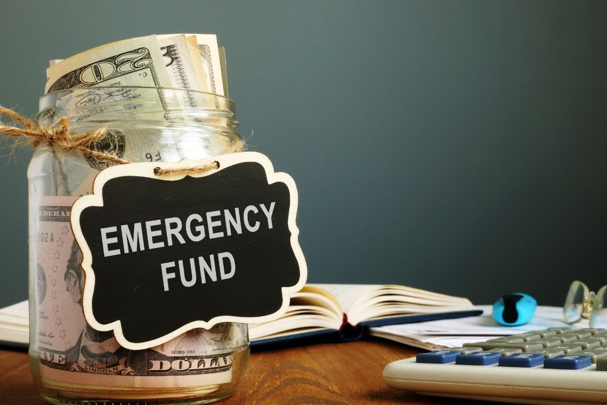 The image of a jar filled with dollar bills and with an emergency fund tag.