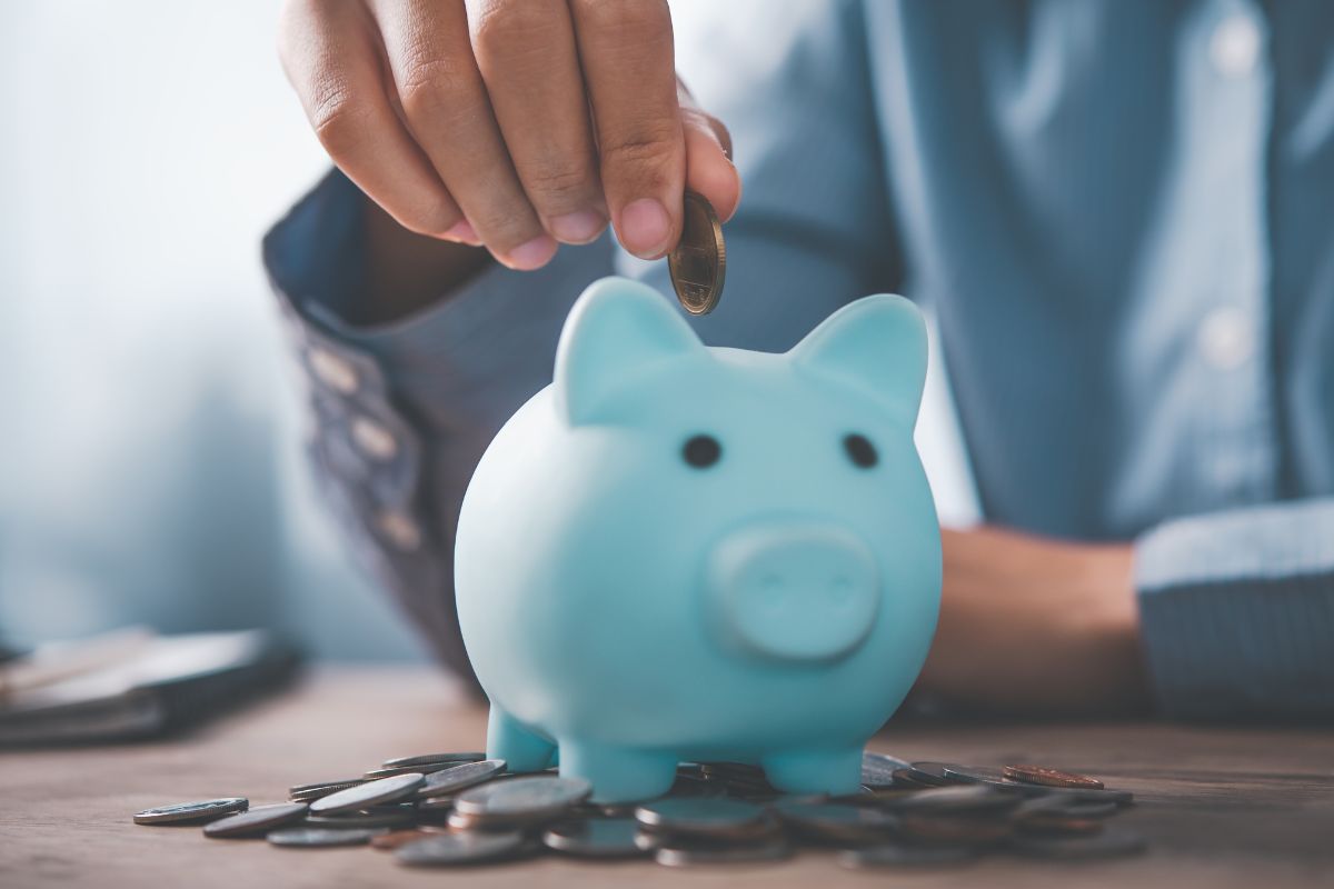 A picture of someone putting coins in a piggy bank.
