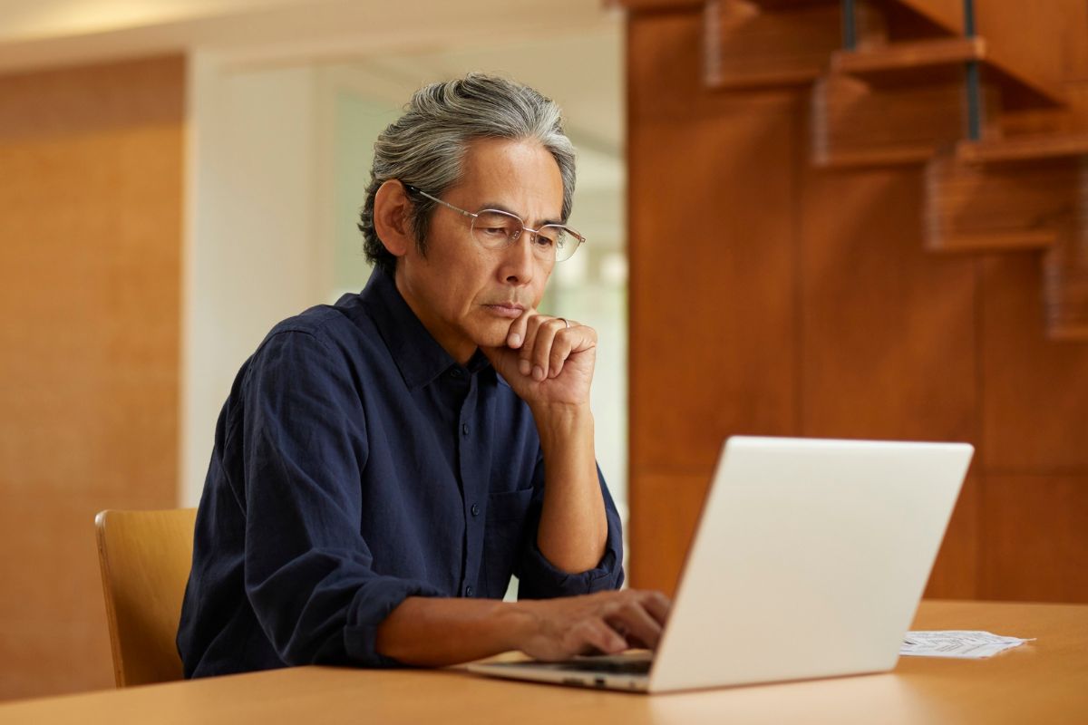 A picture of an old person looking at a laptop. 
