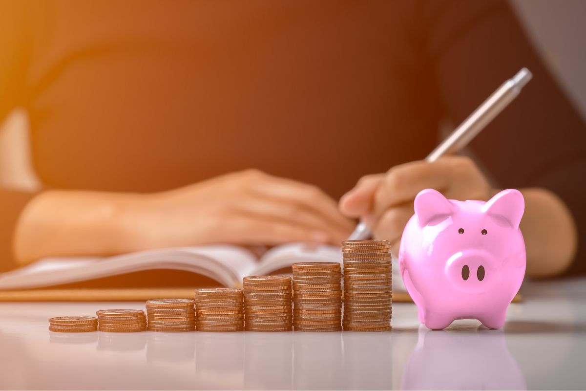 A picture of someone writing and a piggy bank. 