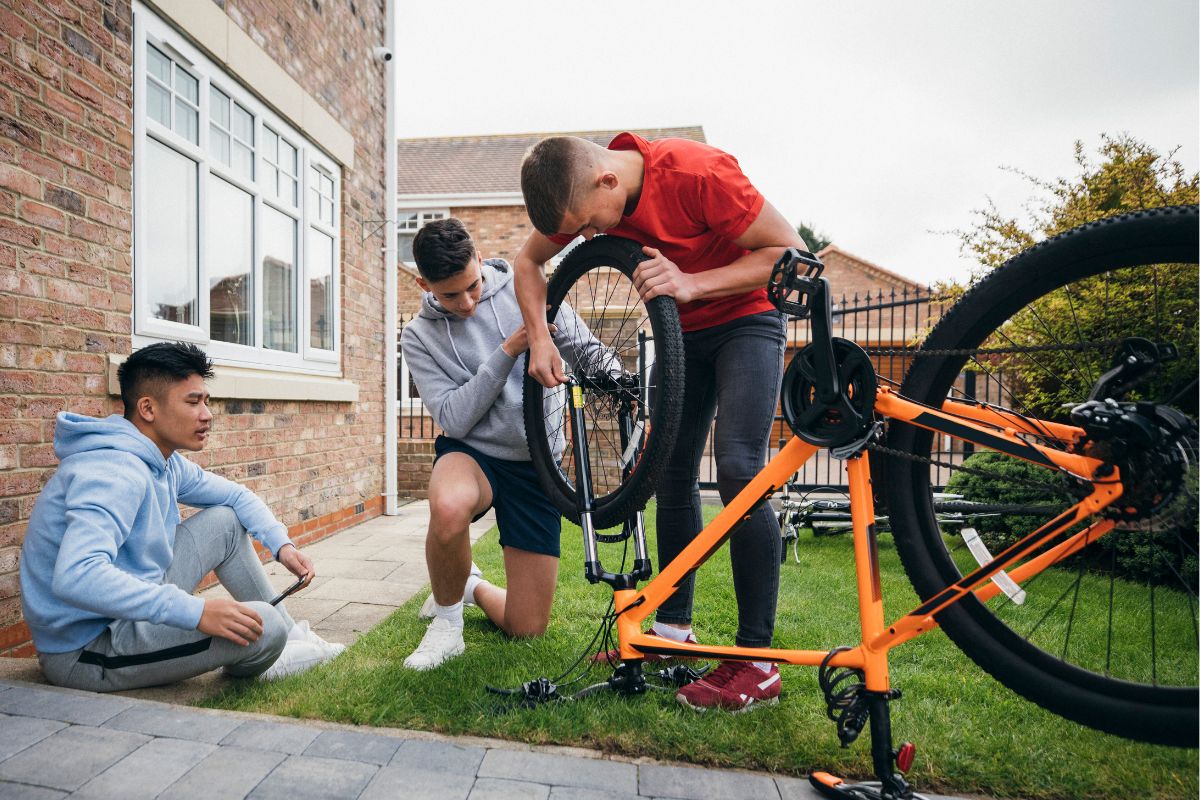 A picture of teenagers fixing a bike.