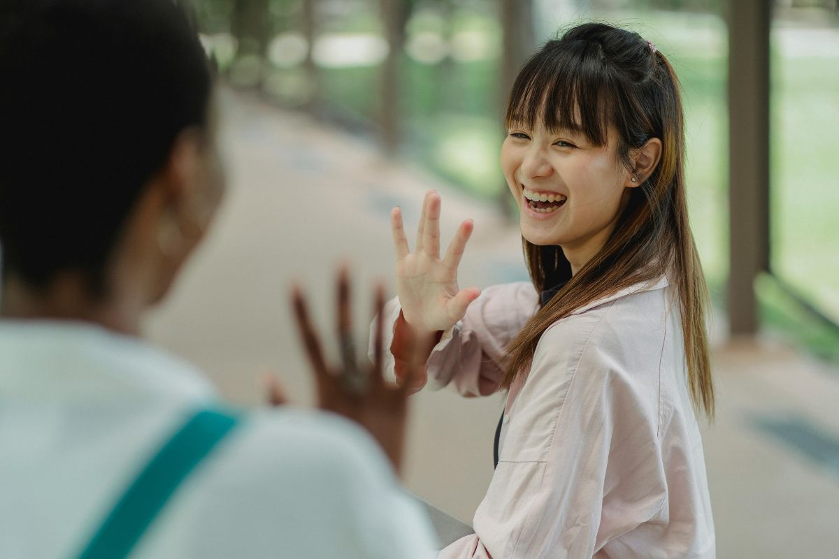 A picture of two people waving at each other. 