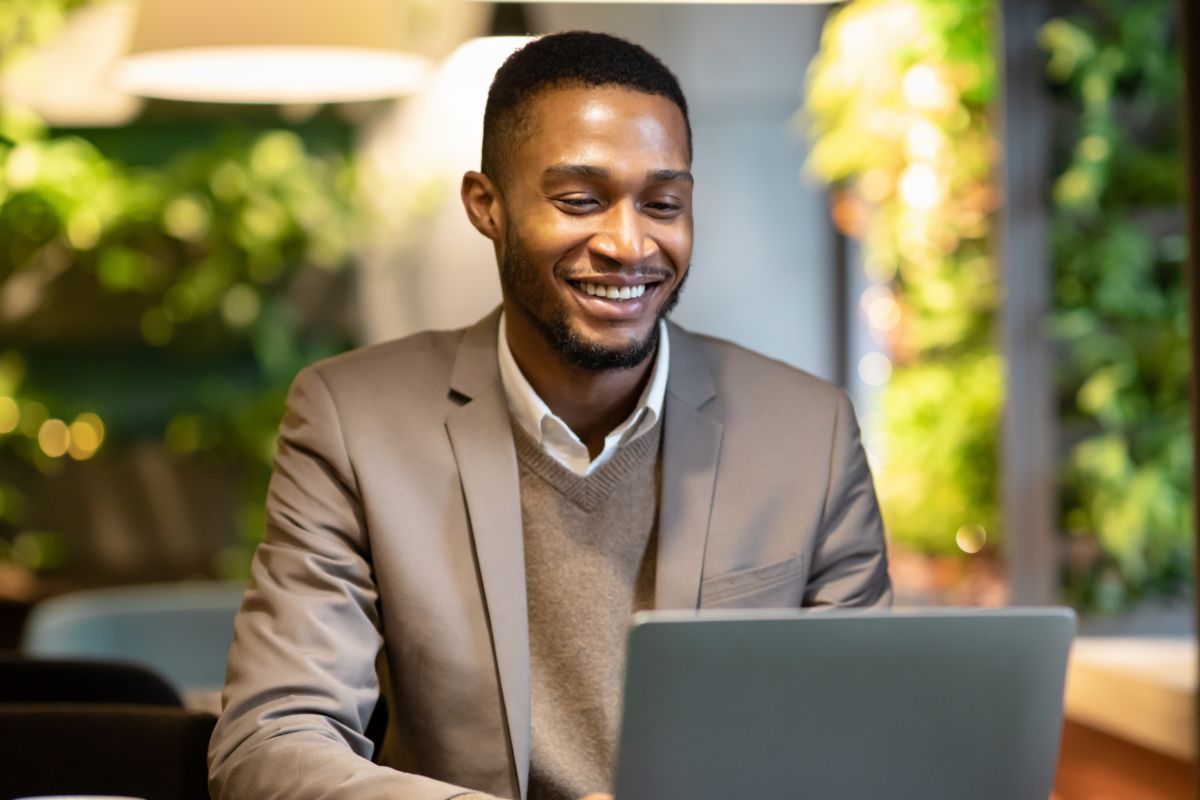 A picture of someone smiling while looking at their laptop. 