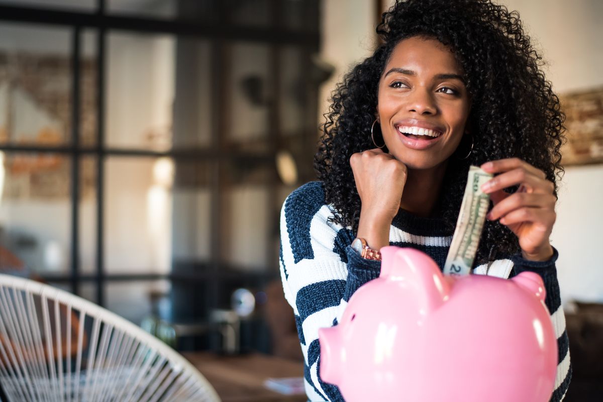 A picture of someone putting money into their piggy bank,