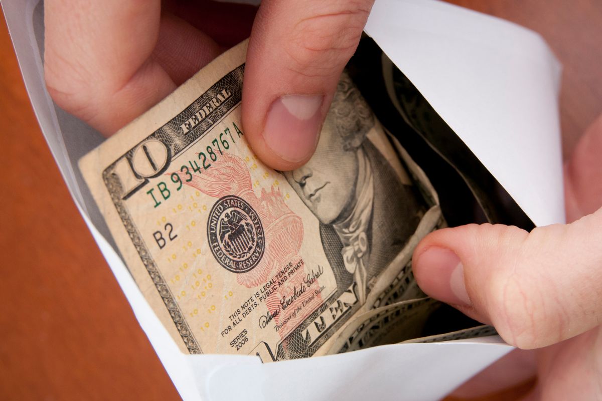 A picture of someone putting money into an envelope. 