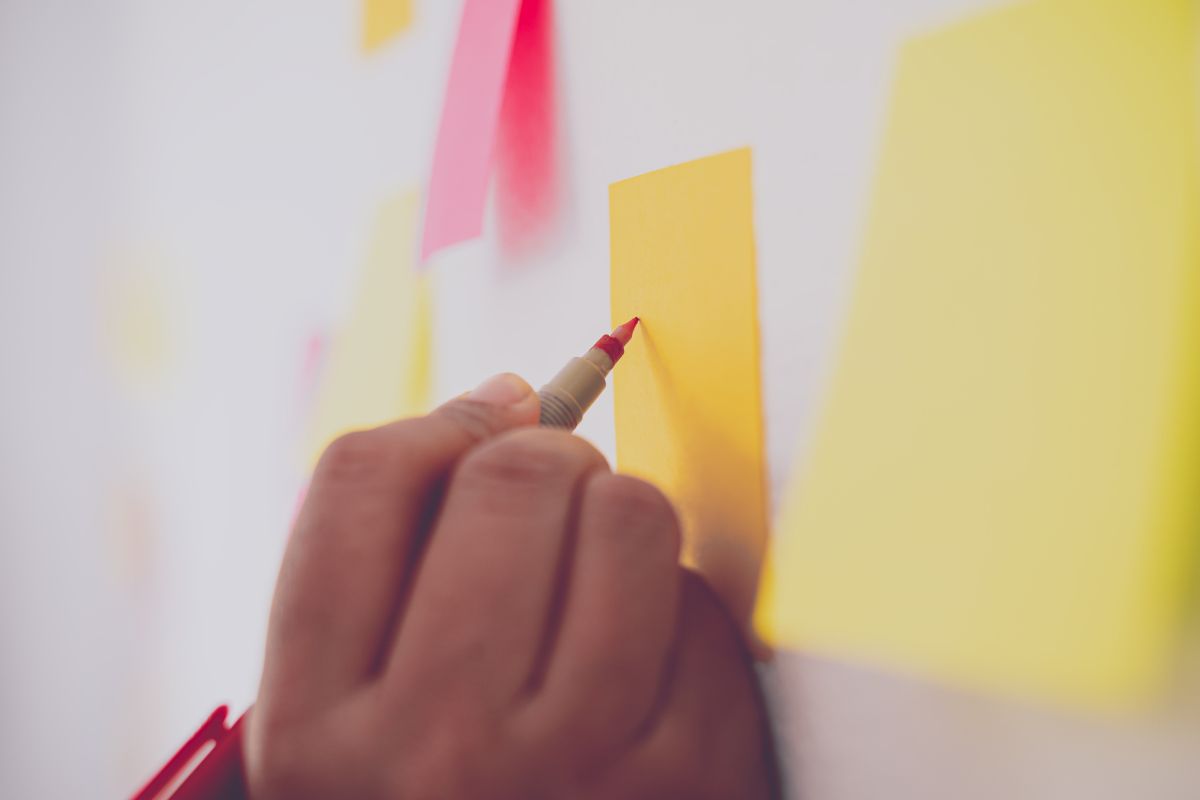 A picture of someone writing on a sticky note.