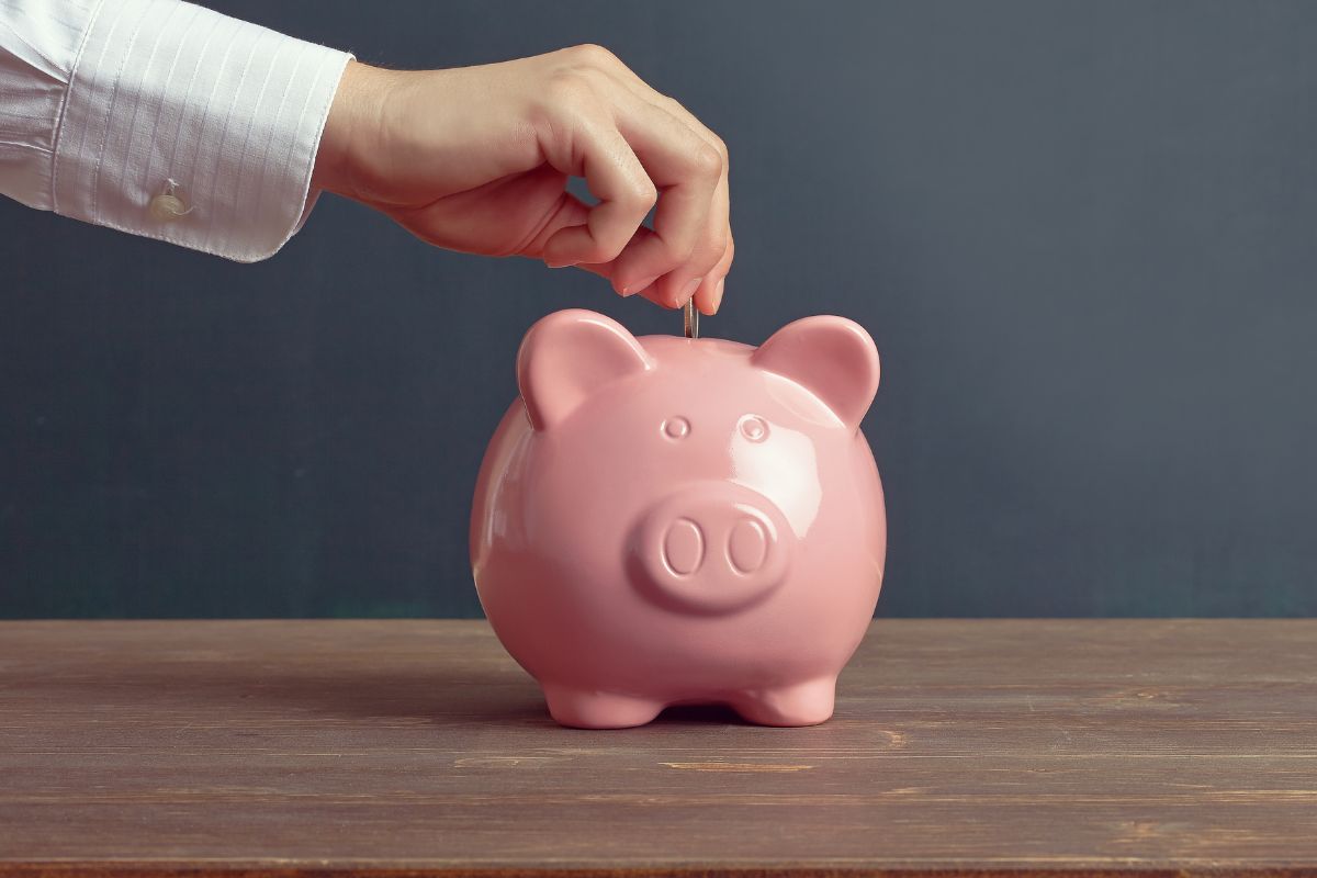 A picture of someone putting money into their piggy bank.