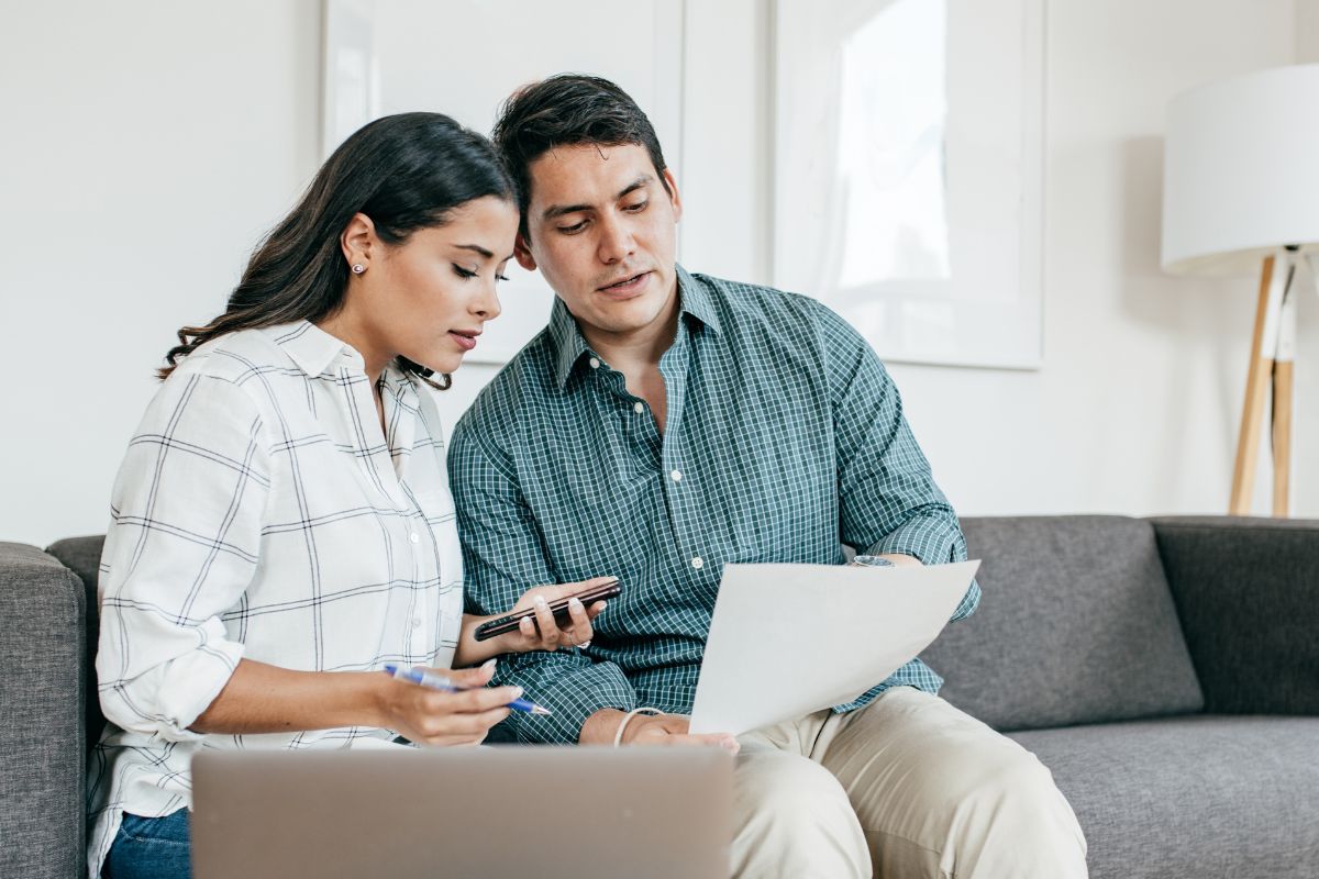 A picture of a couple looking at a paper. 