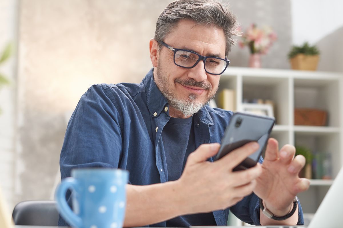 A picture of someone smiling while looking at his phone. 