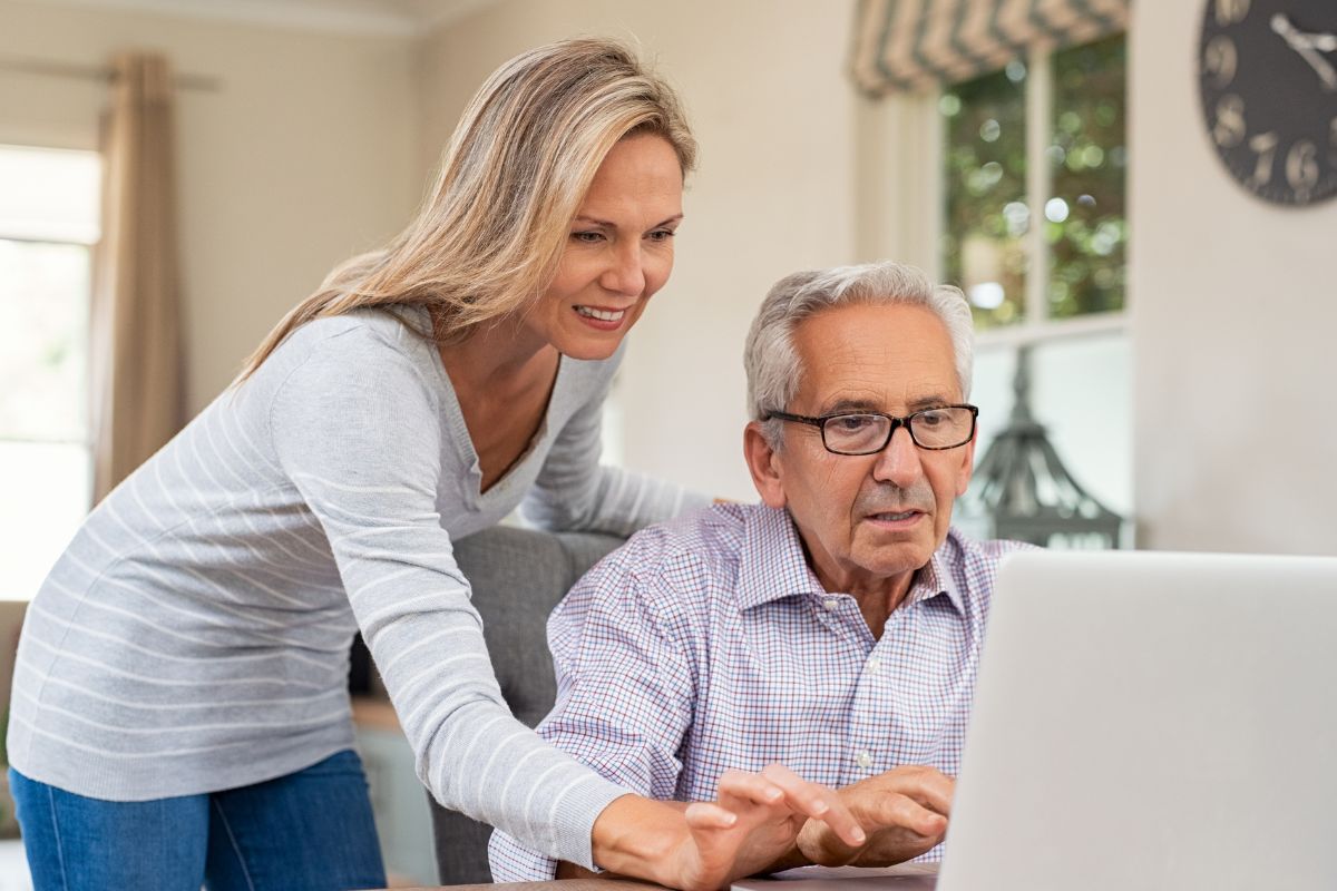 A picture of someone helping an old person with tech.