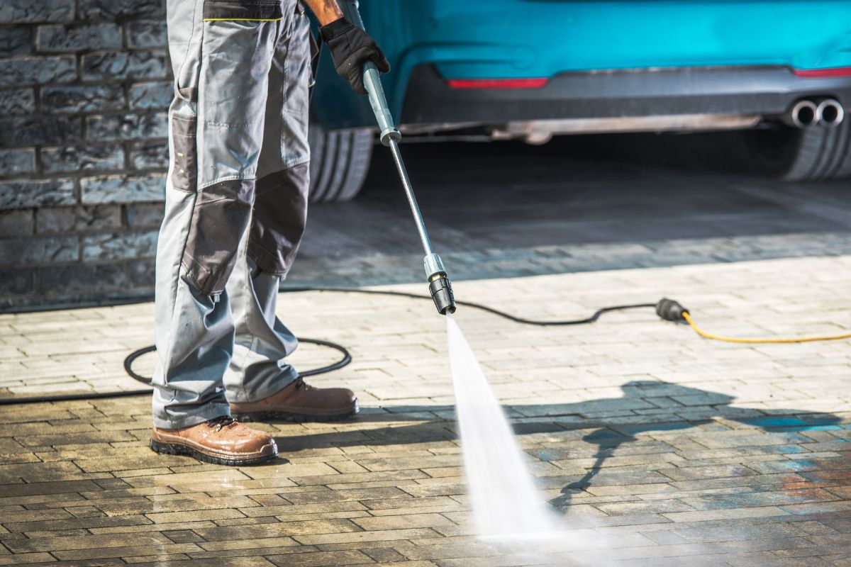 A picture of someone power washing a driveway.