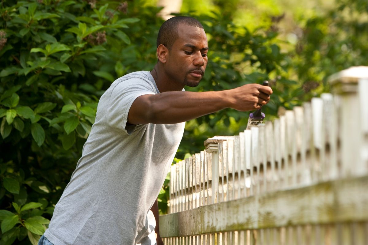 A picture of someone painting a fence. 