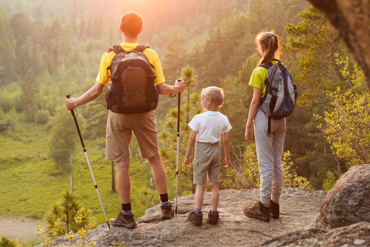 A picture of a father and his kids hiking. 